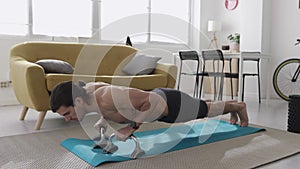 Fitness young man doing plank position using push up stand hand bar at home