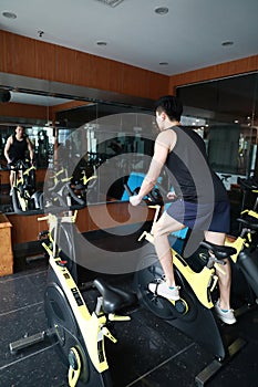 Asian chinese Fitness young man on gym bike spinning