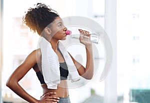 Fitness, young woman athlete and water or bottle for exercise hydration or after workout with towel and in gym