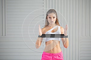 Fitness young woman doing back exercise with resistance band for training strength. Female athete exercising