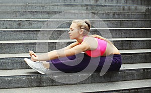 Fitness young woman doing warm-up legs stretching exercise before run, female athlete ready to workout in city - sport and healthy