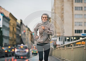 Fitness young woman jogging in rainy city