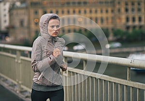 Fitness young woman jogging in rainy city