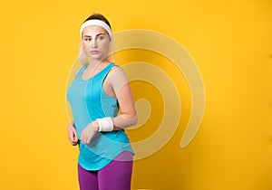 Fitness young woman posing and looking to side, isolated on yellow background. Half length of sportswoman ready for exercising.