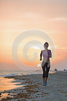 Fitness young woman running on beach in the evening