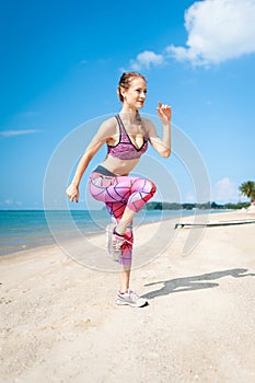 Fitness young woman working out core and glutes with bodyweight workout doing squat exercises on beach