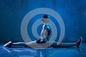 Fitnesswoman practicing split under rain.