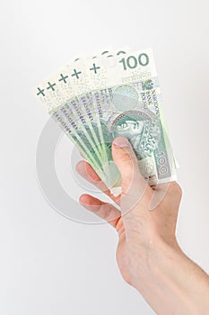 Five 100 PLN banknotes held in right hand