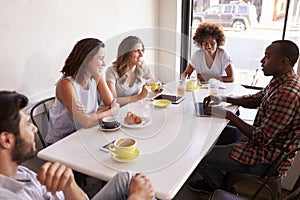 Five adult friends sitting in a cafe, elevated view close up