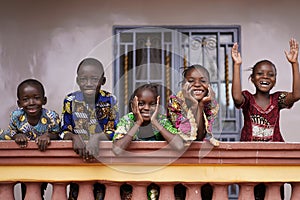 Five African Children Greeting Bypassers From A Colonial House Balcony