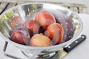 Amigo Pluot Fruits in a Stainless Steel Strainer with Knife photo
