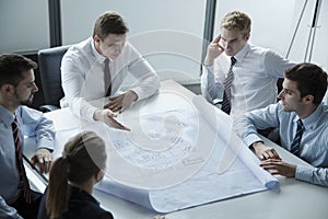 Five architects discussing and planning over a blueprint in the office