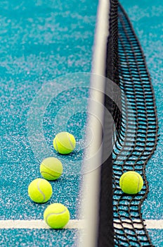 five balls next to the net of a paddle tennis court, racket sports concept