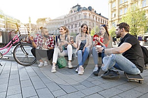 Five best friends have a gathering in the city street drinking take away coffee to go