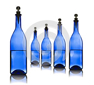 Five blue glass bottles with water on a white