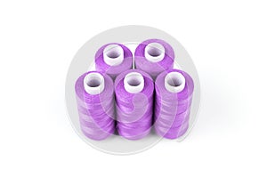 Five bright purple sewing threads on a white coils on a white background. Sewing supplies, magenta