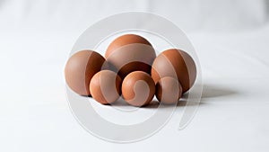 Five brown spheres of varying sizes arranged on a white surface