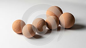 Five brown spherical objects of varying sizes are arranged on a white surface