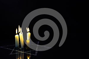 Five burning candles and the Star of David against a black background.