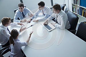 Five business people having a business meeting at the table in the office