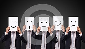 Five businessman holding a card with drawing facial expressions different emotion feelings face on white paper photo