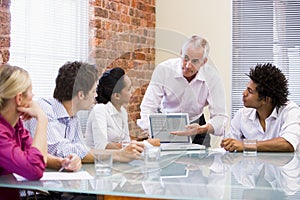 Five businesspeople in boardroom with laptop