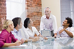 Five businesspeople in boardroom with laptop