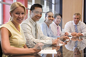 Five businesspeople in boardroom smiling