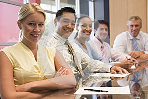 Five businesspeople at boardroom table smiling