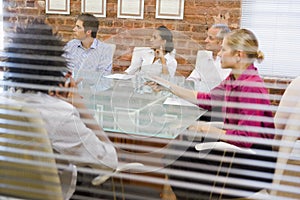 Five businesspeople in boardroom through window