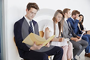 Five candidates sit waiting for job interviews, close up