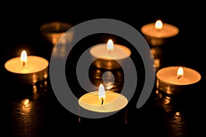 Five candles Burning out of six on dark table, black background, Memory day.