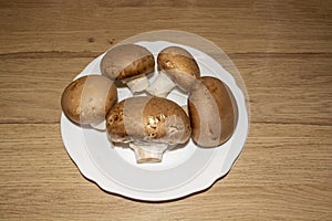 Five champignons on a plate on a wooden countertop