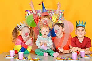 Five children celebrate a birthday at the table with a clown