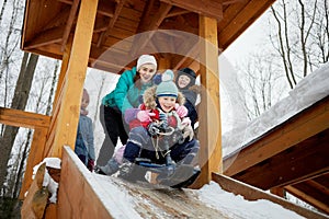 Five children sled from wooden slide covered with