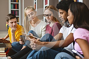 Five classmates reading lecture notes, sitting on library floor