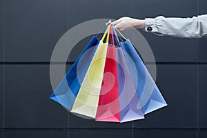 Five colored bags for shopping in a female hand. Close-up. Shopping