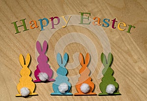 Five colorful wooden Easter bunnies in a row on a wooden underground