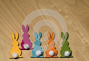 Five colorful wooden Easter bunnies in a row on a wooden underground