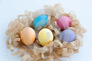 Five colourful eggs in the hay nest on white background. Isolated. Blue, Yellow, Orange, Pink, Violet