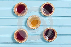 Five colourful jam tarts on a blue background
