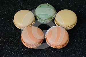 Five colourful macaroons are on the black background. Five tasty cookies