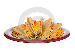 Five crispy tacos on a red plate isolated