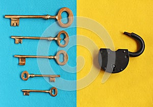 Five different golden vintage keys on blue felt and open padlock