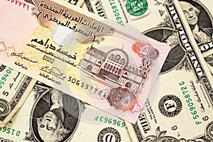 A five dirham bank note from United Arab Emirates on a background of American one dollar bills