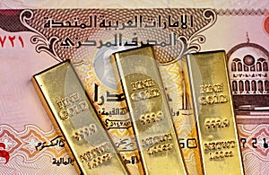 A five dirham bank note from the United Arab Emirates with three small gold bars