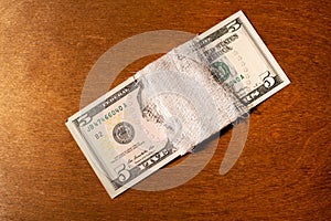 Five-dollar bills bandaged with a bandage on a wooden background.