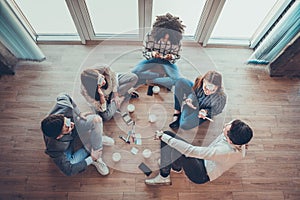 Five employees sitting on the floor with legs crossed and doing brainstorming