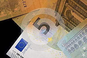 Five euro banknotes on a dark background. Money background brown color toned