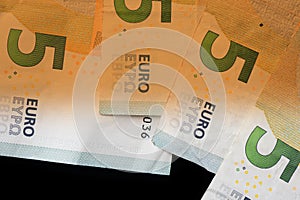 Five euro banknotes on a dark background. Money background brown color toned